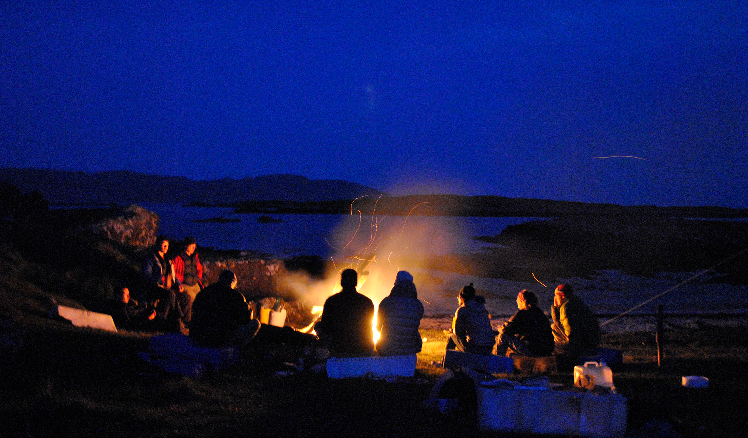 People sat around campfire at night